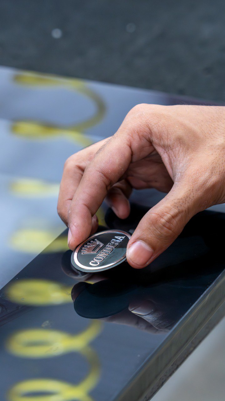 Mano colocando un emblema sobre una superficie de vidrio negro